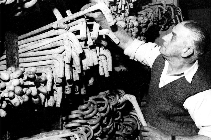 Black and white image of a man stacking walking sticks