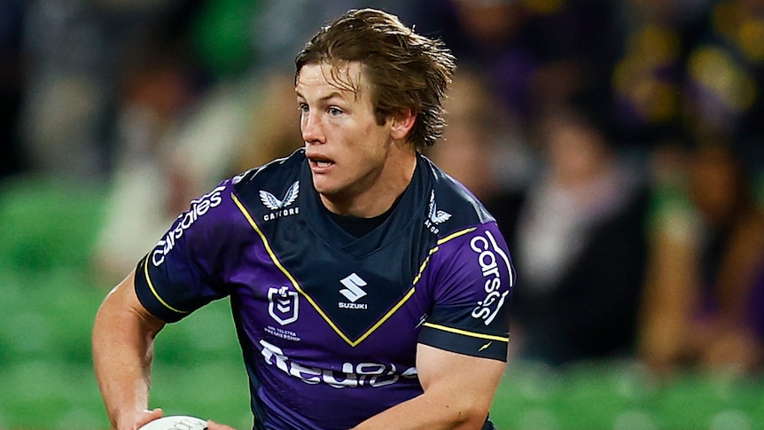 A Melbourne Storm NRL player holds the ball in two hands during a match in 2022.