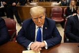 Donald Trump scowls at the camera sitting in court in a suit.
