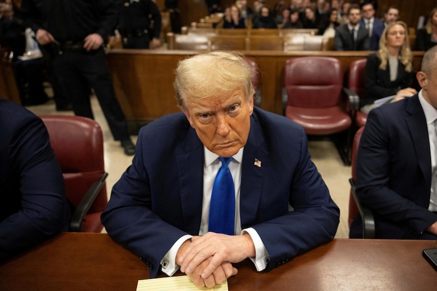 Donald Trump scowls at the camera sitting in court in a suit.