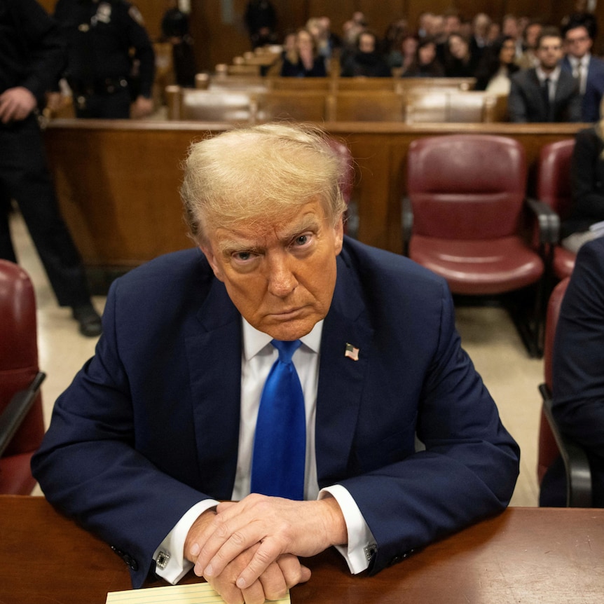 Donald Trump scowls at the camera sitting in court in a suit.