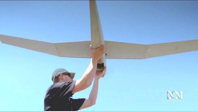 A man holds up a large winged drone aircraft