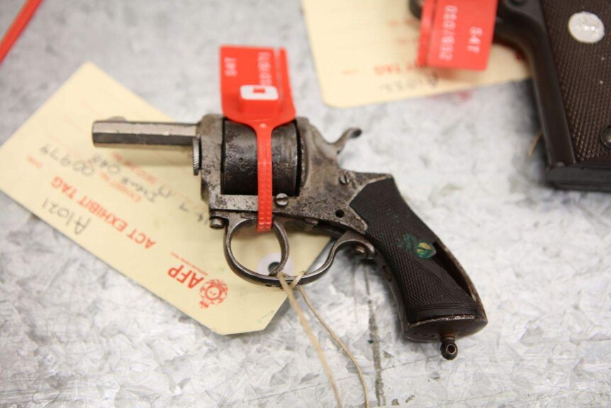 Close up of an old hand gun with a red tag and ACT Police exhibit tag attached