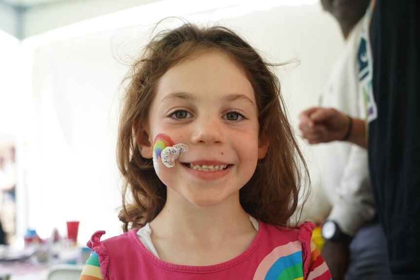 girl with rainbow painted on cheek