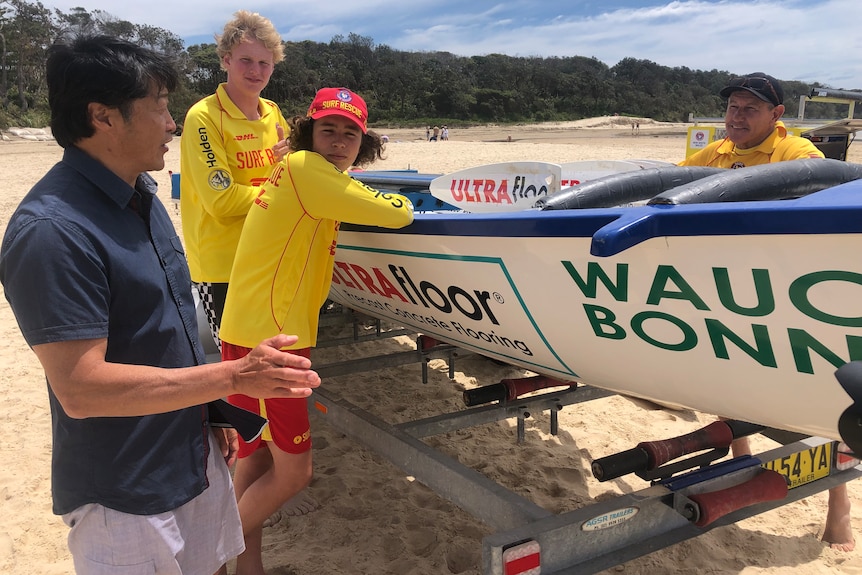 Andrew Bau talking to his rescuers around a surf boat