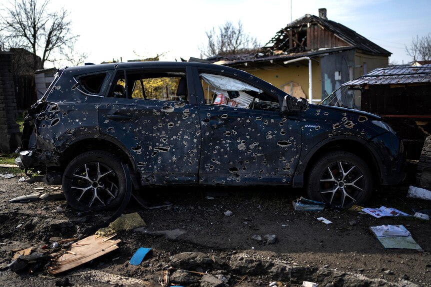 A black car covered in bullet holes.