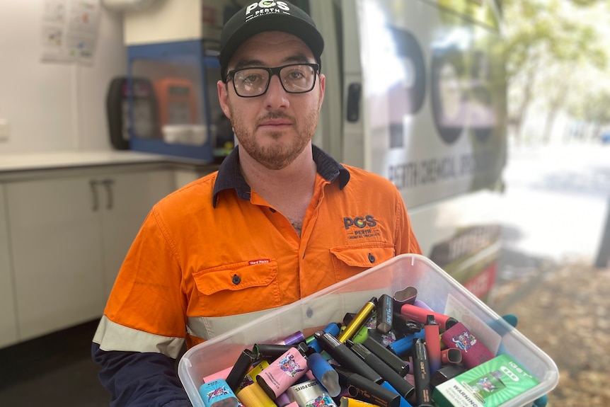 man wearing hi vis clothing holding bucket of discarded vapes 