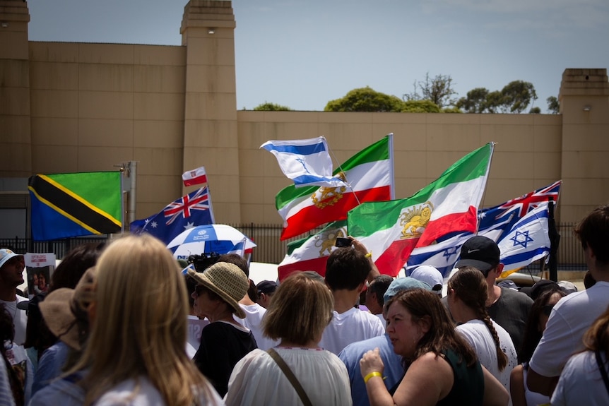 people carrying flags from various countries of those kidnapped by Hamas at a rally in sydney's moore park