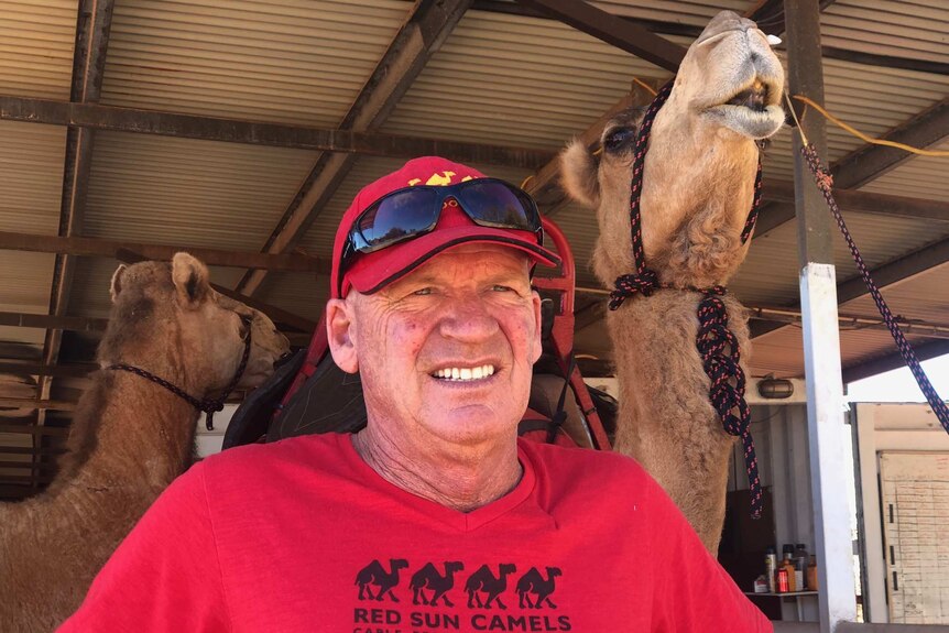 Camel tour operator John Geappen with one of his camels standing behind him