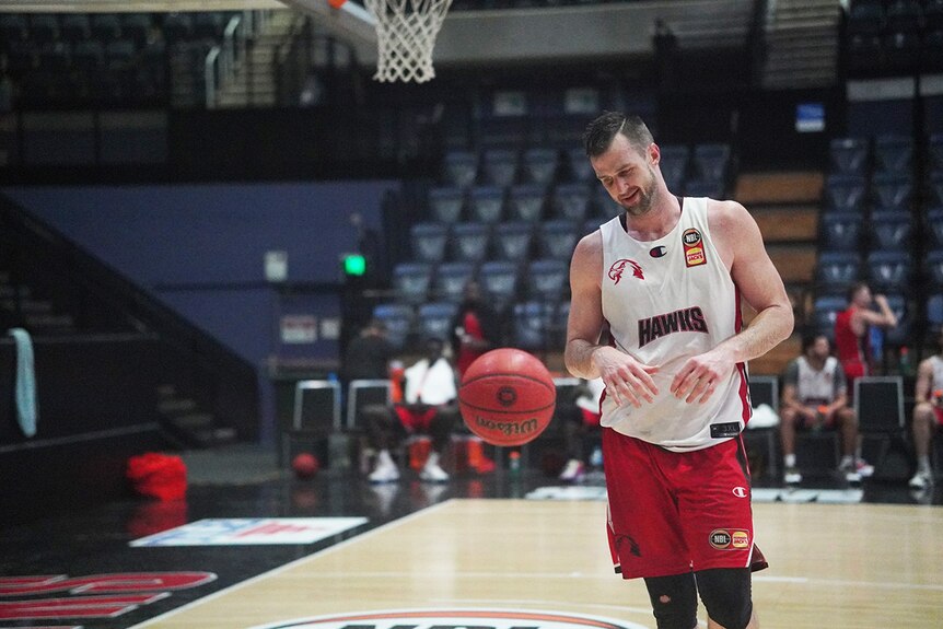 AJ Ogilvy trains with a basketball bouncing in front of him.
