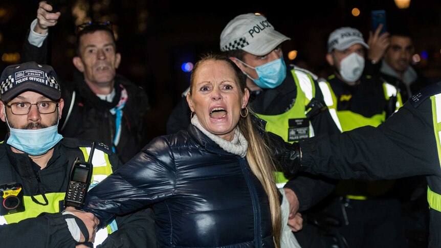 Police arrest a woman taking part in the annual 'Million Mask March' coinciding with the first day of coronavirus lockdown.