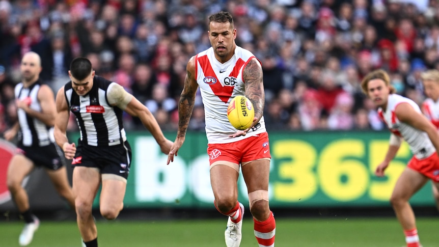 Lance Franklin carries the ball for Sydney Swans against Collingwood in front of a big stadium crowd