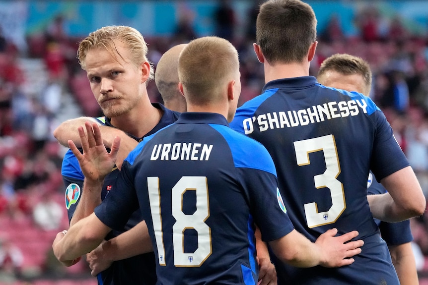 Joel Pohjanpalo holds his hand up as teammates hug him