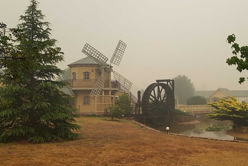 A rural property featuring a windmill, dam and water wheel.