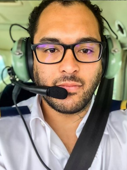 Headshot of a male pilot sits in a small aircraft wearing a headset.