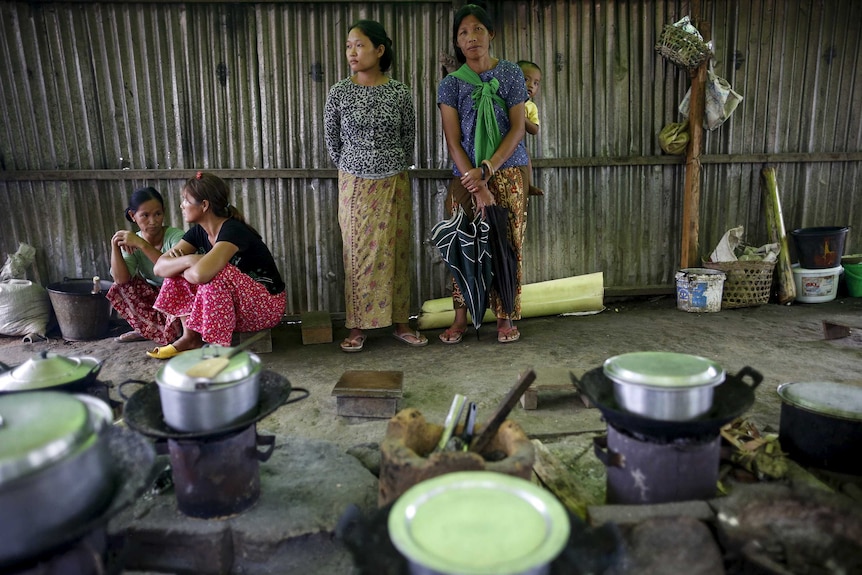 克钦族女性站在一个专门安置流离失所者的营地的公用厨房里。