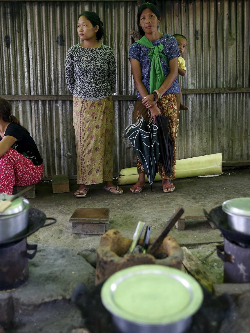 Women pass time in a rudimentary, dirt floor kitchen in a Kachin state refugee camp.