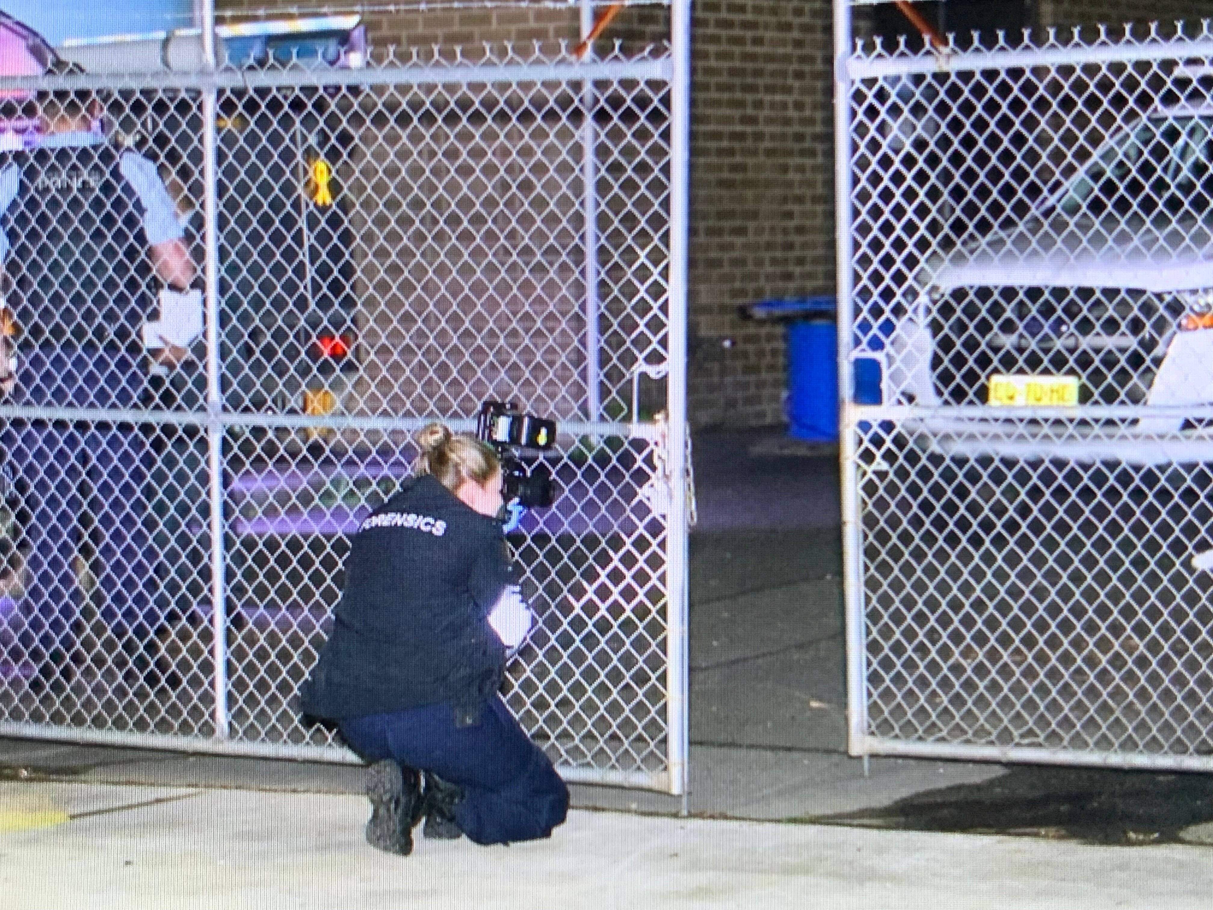 A female police officer is crouched conducting an investigation.
