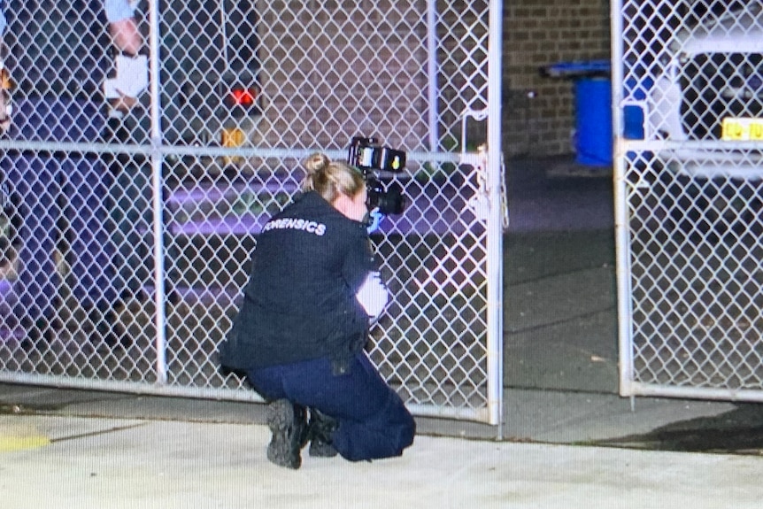 A female police officer is crouched conducting an investigation.