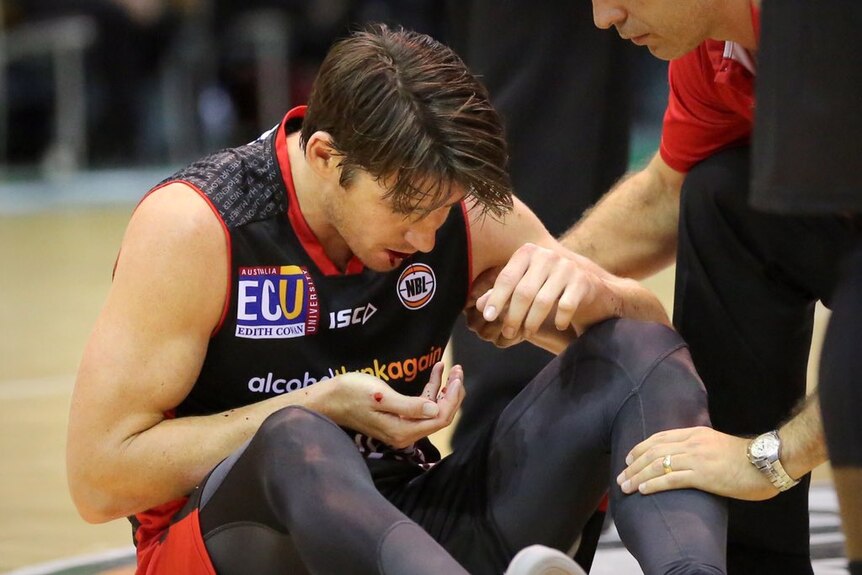Damian Martin sits on the ground bleeding from the mouth at a match.
