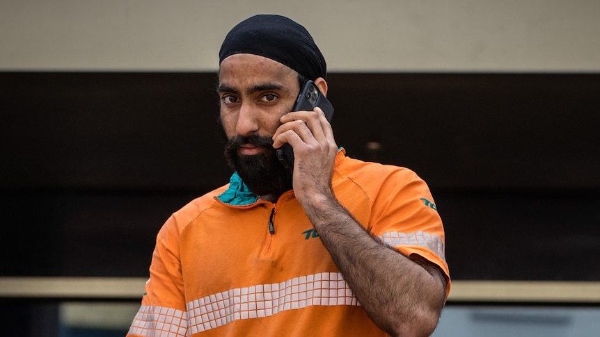 Paramveer Singh walks while holding his phone.