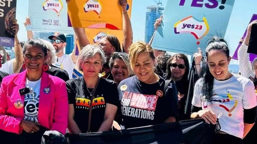 A groupd of Indigenous women are holding big bright signs that say Yes 23