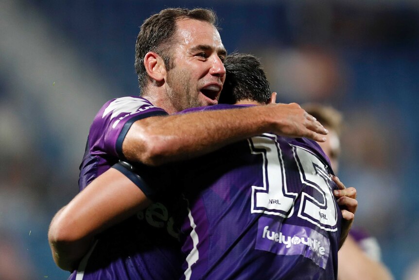 Two Melbourne Storm NRL players embrace after scoring a try against Wests Tigers.