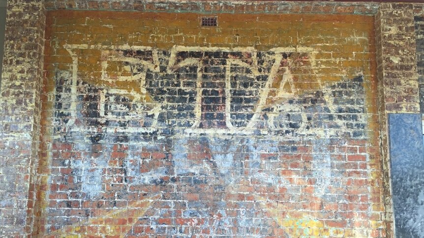 A sign for ETA peanut butter, which has been painted over a Velvet Soap sign, uncovered on the side of building.
