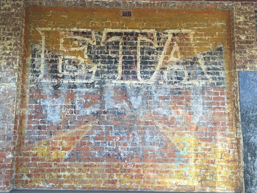 A sign for ETA peanut butter, which has been painted over a Velvet Soap sign, uncovered on the side of building.