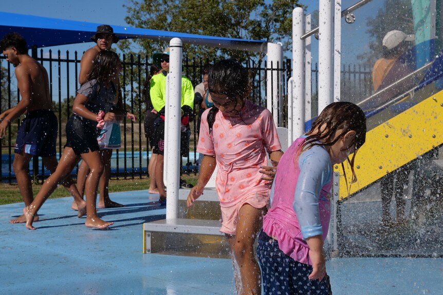 Kids underneath a sprinkler within the splash pool