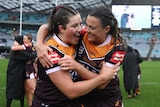 Brisbane Broncos NRLW players Chelsea Lenarduzzi and Millie Boyle hug and smile in the rain after winning the grand final.