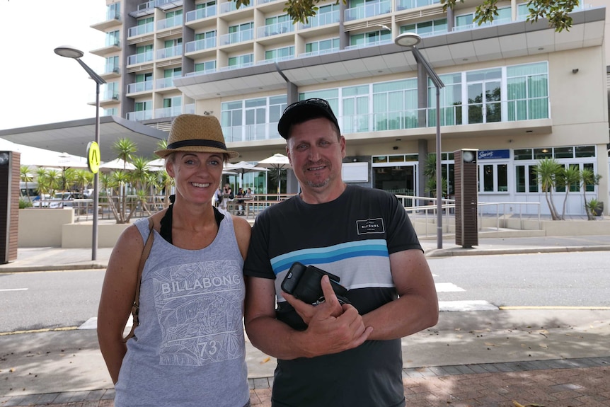 A woman and a man stand together in front of large building