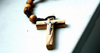 Close up of a crucifix on rosary bead chain.