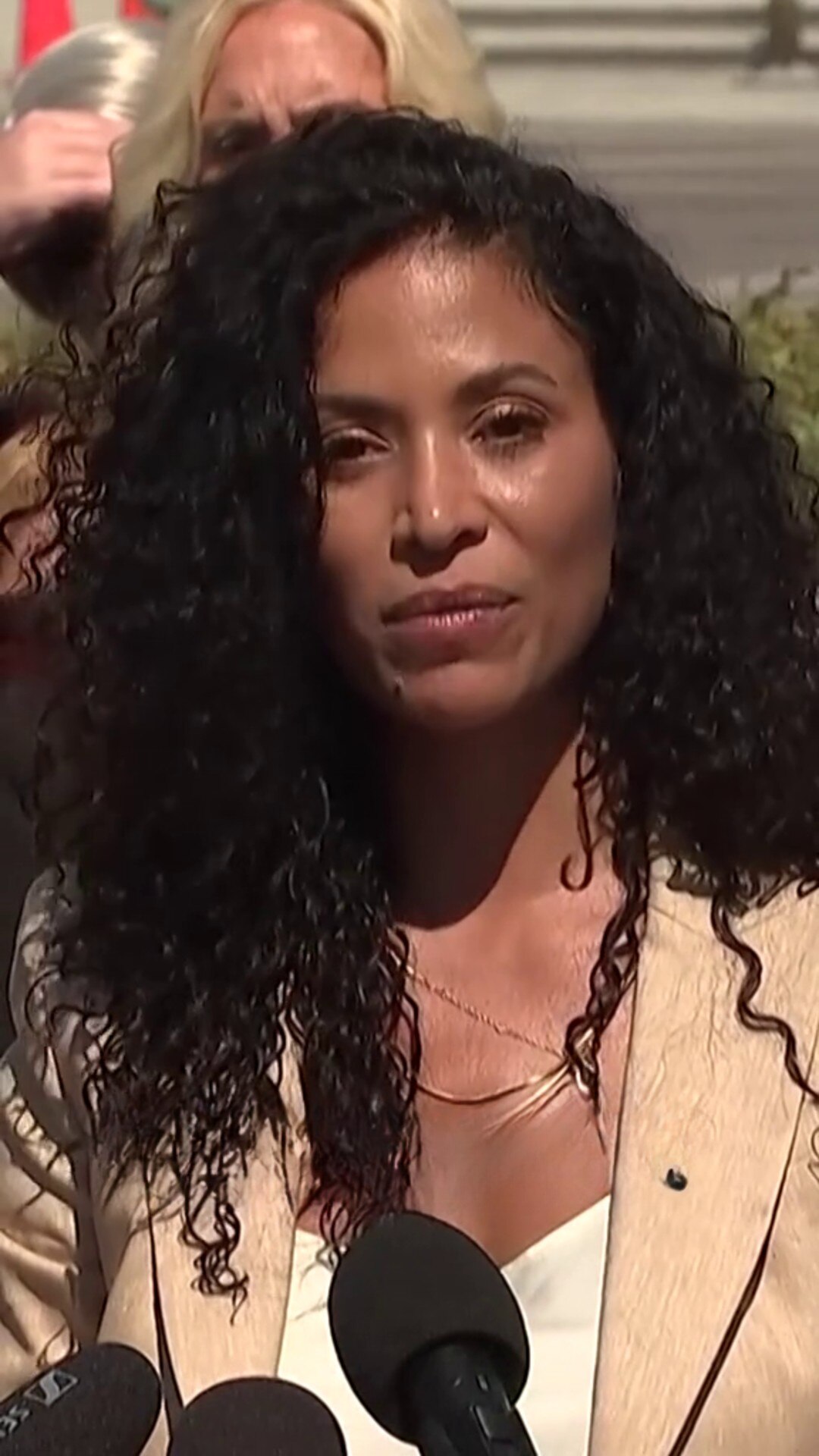 Close up of a beautiful woman with dark skin and curly black hair, staring defiantly into the camera.