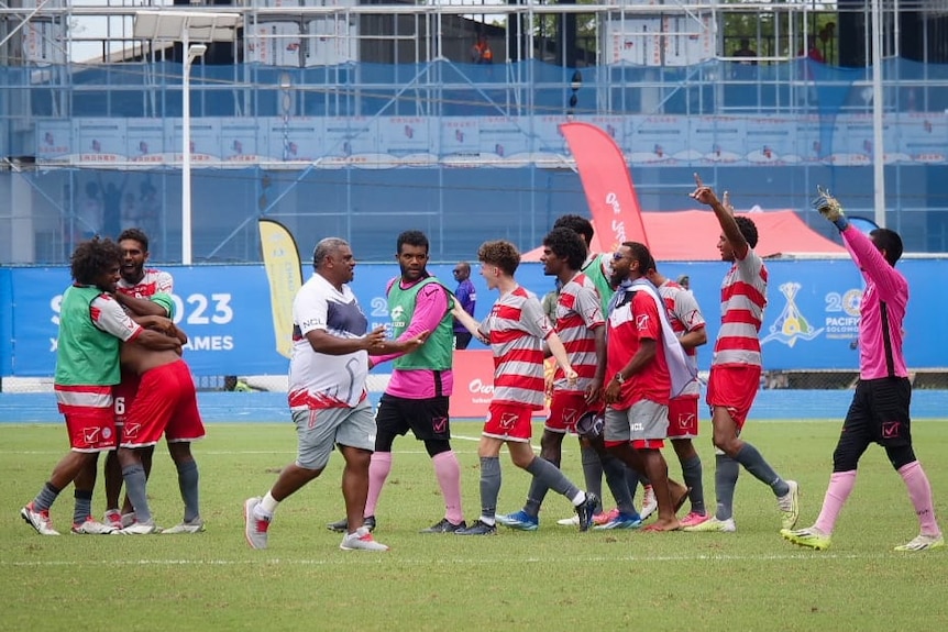 A group of New Caledonian players walk on the field together, celebrating.