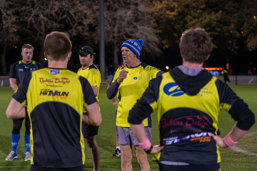 a group of men stand around a coach