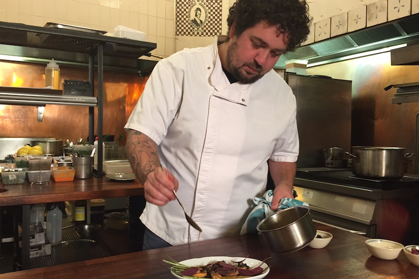 Adelaide chef Duncan Welgemoed prepares meal in restaurant kitchen.