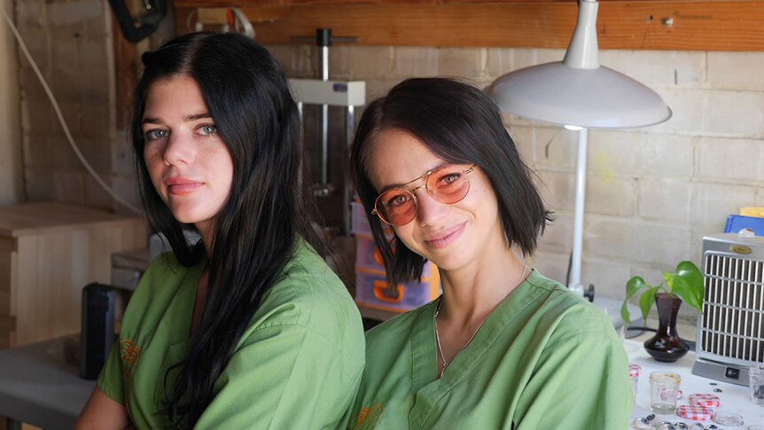 Two women in green medical scrubs in a workshop.