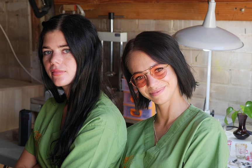 Two women in green medical scrubs in a workshop.