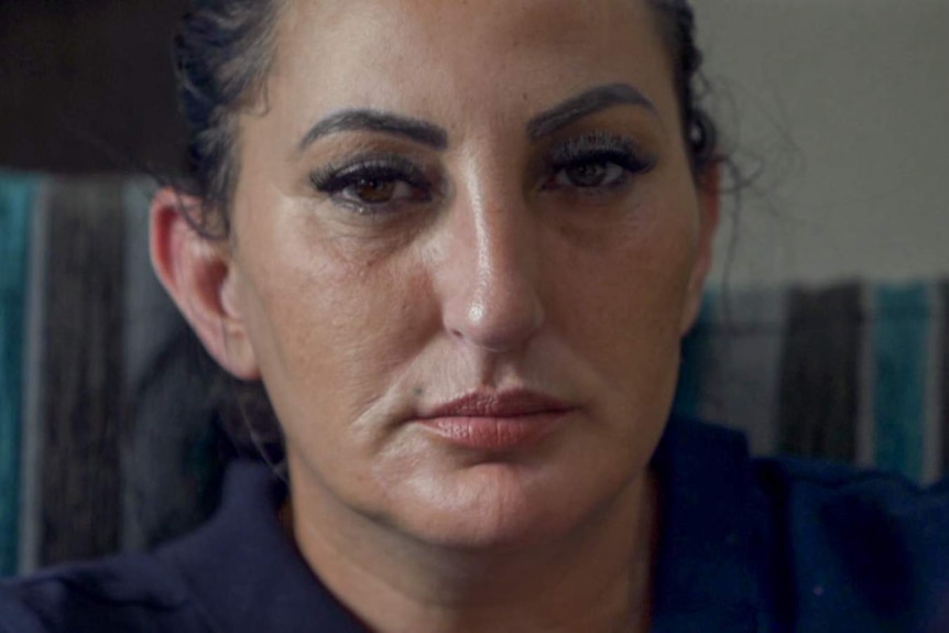 Woman wearing black mascara with black hair stares without smiling