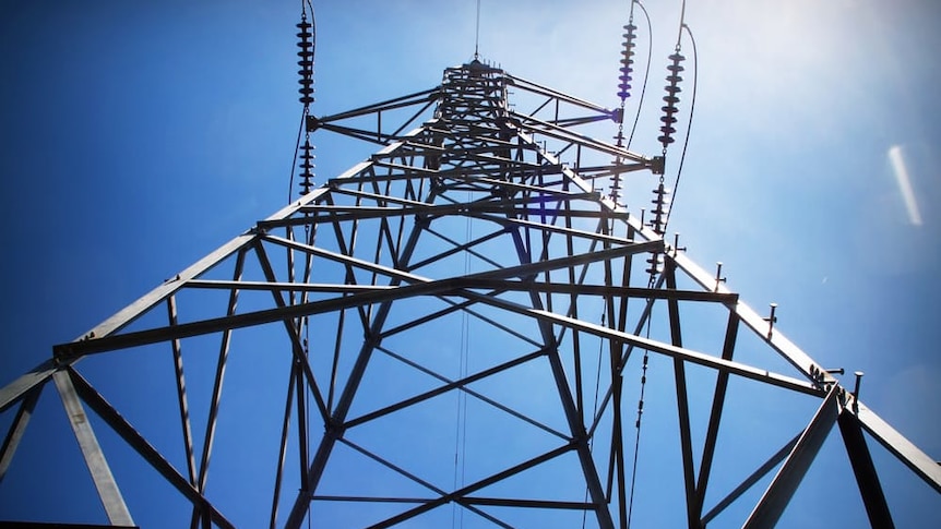 An electricity tower, as seen from below, rises into blue sky.