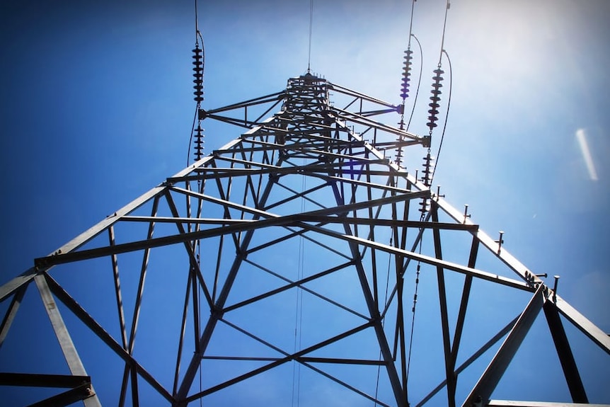 An electricity tower, as seen from below, rises into a blue sky.