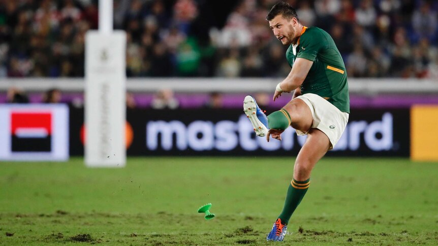 A South African rugby player follows through his leg after kicking the ball from the tee in the Rugby World Cup final.