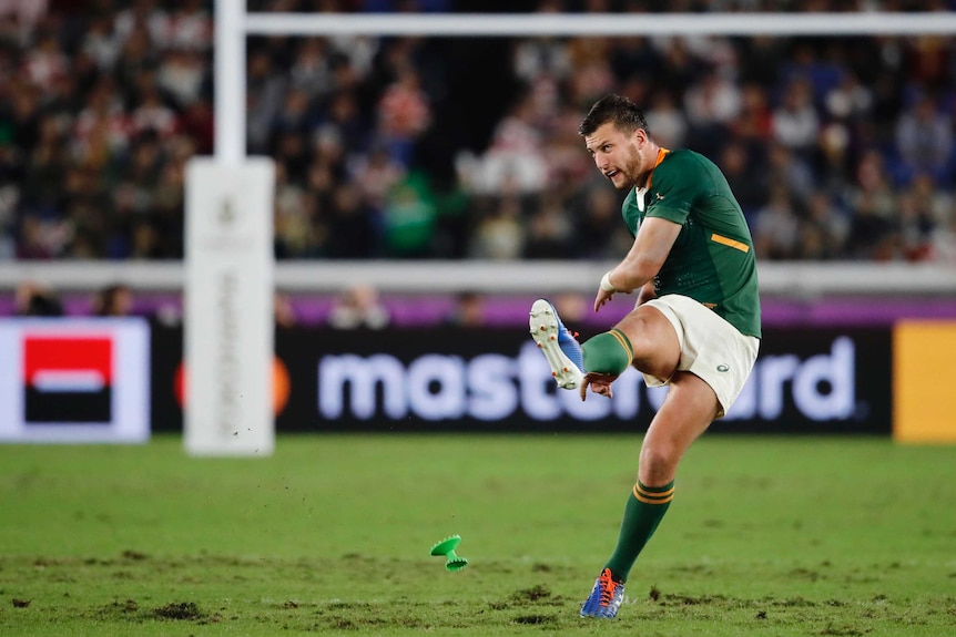 A South African rugby player follows through his leg after kicking the ball from the tee in the Rugby World Cup final.