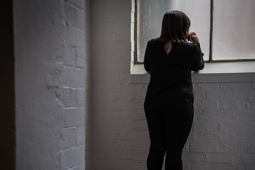 Sarah stands next to a window