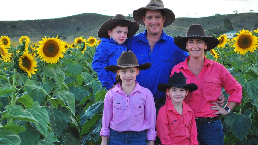 The McNaughton family standing in a field of sunflowers.