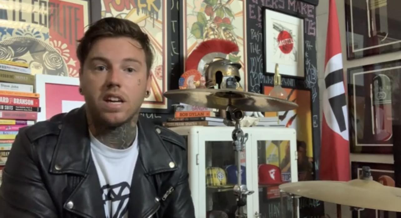 Shane Cuthbert sits near a Nazi flag.