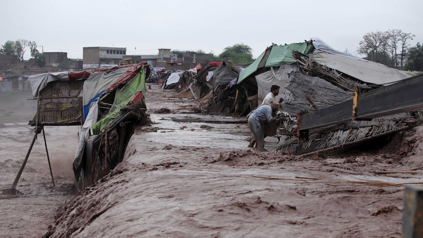 Men collect their belongings from their makeshift shop which was damaged by flood water.