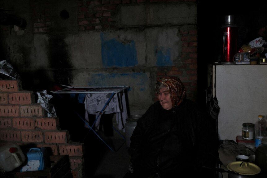 a woman sits in a dark basement 