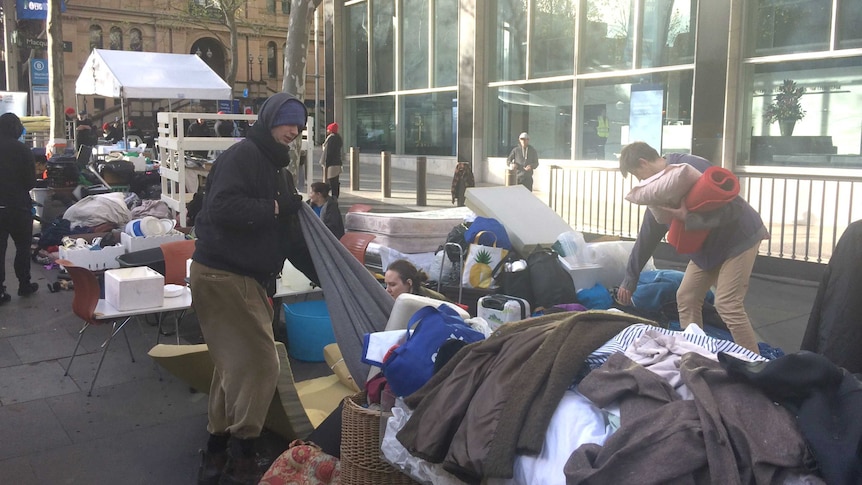 Homeless people in Martin Place  packing up blankets and clothes.